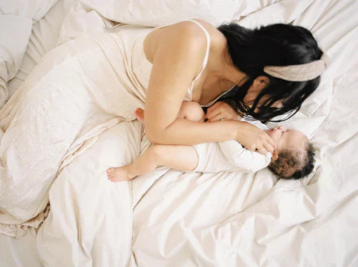A mother gently holding her baby on a bed, illustrating an article about understanding and managing GERD in babies.