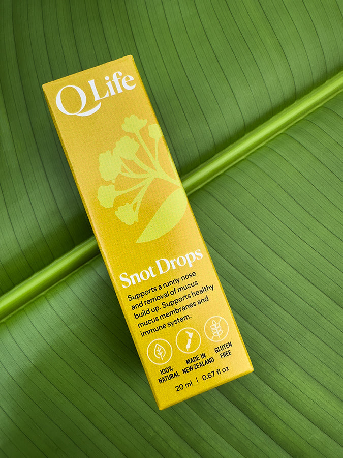 Q Life Snot Drops box on a green leaf, highlighting the product's natural ingredients.